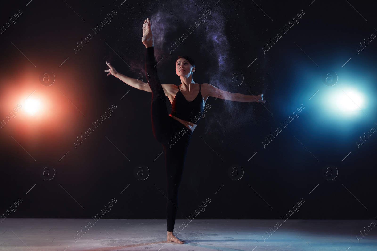 Photo of Professional acrobat with chalk powder exercising in dark studio