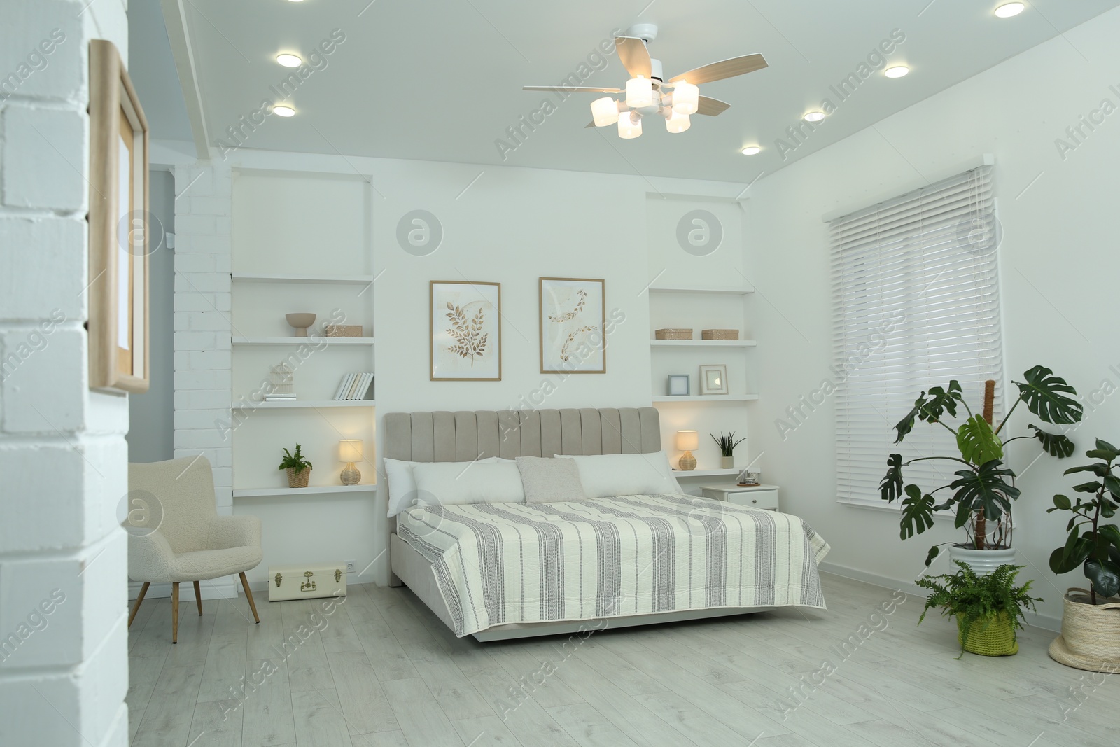 Photo of Comfortable furniture, ceiling fan, houseplants and accessories in stylish bedroom