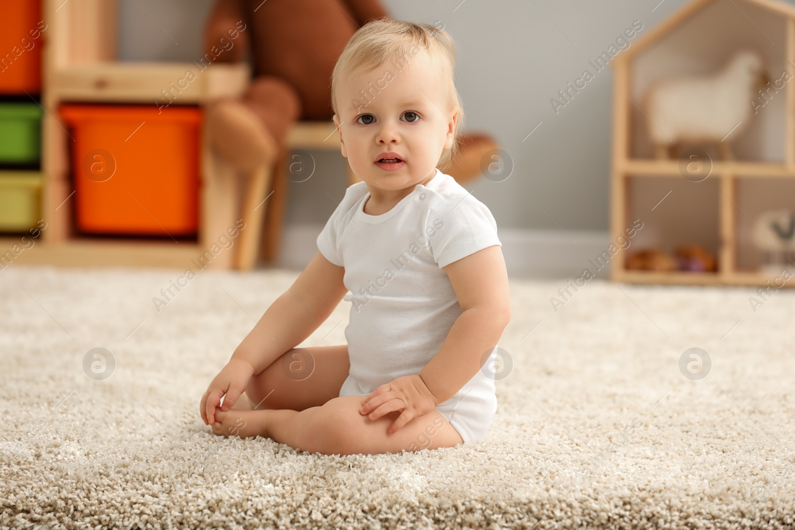 Photo of Cute little boy on rug in children's room