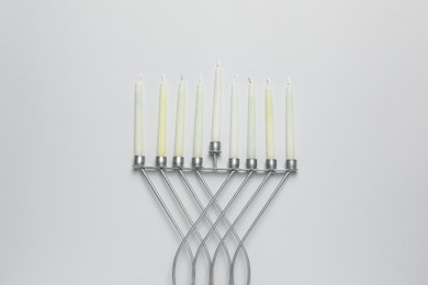 Hanukkah menorah with candles on light background, flat lay