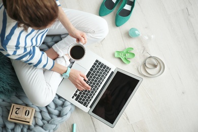 Photo of Female blogger with laptop and cup of coffee indoors, top view