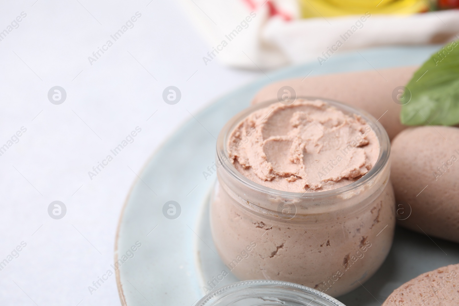 Photo of Delicious liver sausages and paste on white table, closeup. Space for text