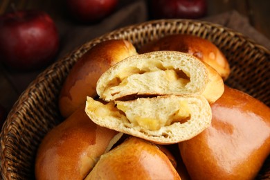 Photo of Delicious baked apple pirozhki in wicker basket, closeup