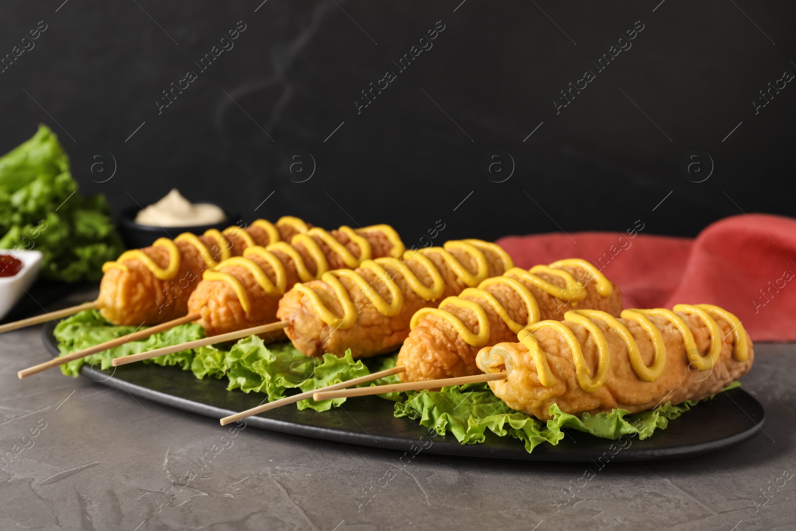 Photo of Delicious corn dogs with mustard served on grey table