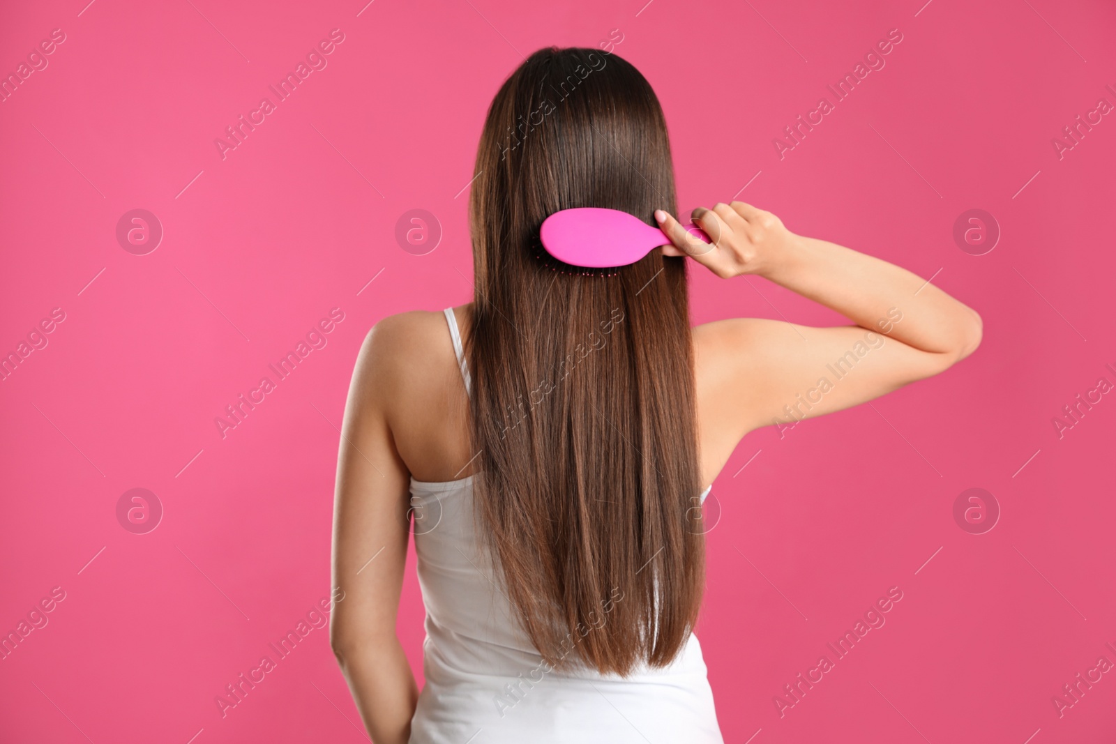 Photo of Back view of young woman with hair brush on color background