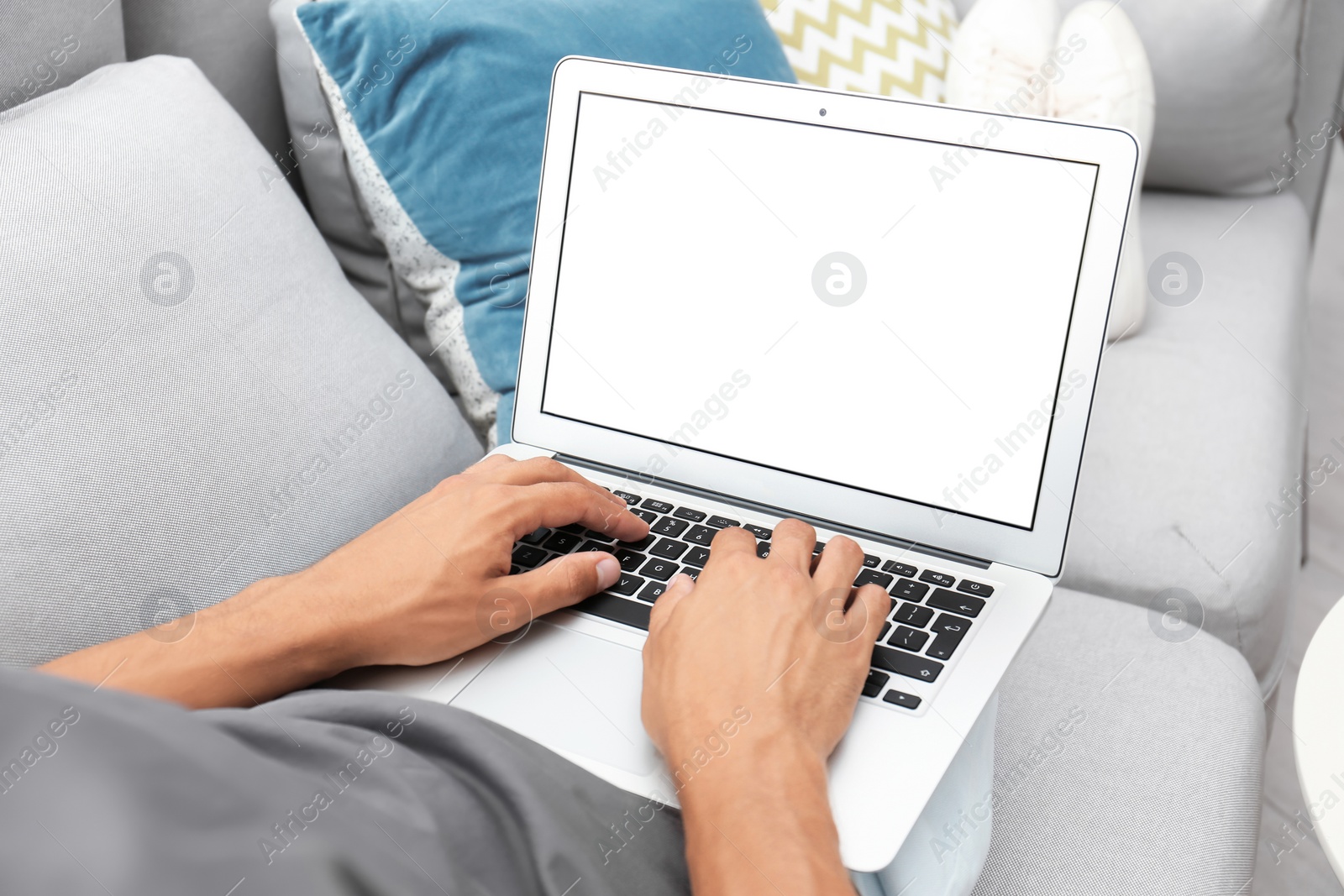 Photo of Man in casual clothes using laptop on sofa at home