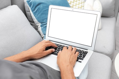 Man in casual clothes using laptop on sofa at home