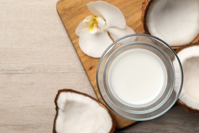 Photo of Glass of delicious vegan milk, coconuts and flower on white wooden table, flat lay. Space for text