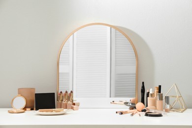 Photo of Stylish mirror on dressing table with cosmetic products
