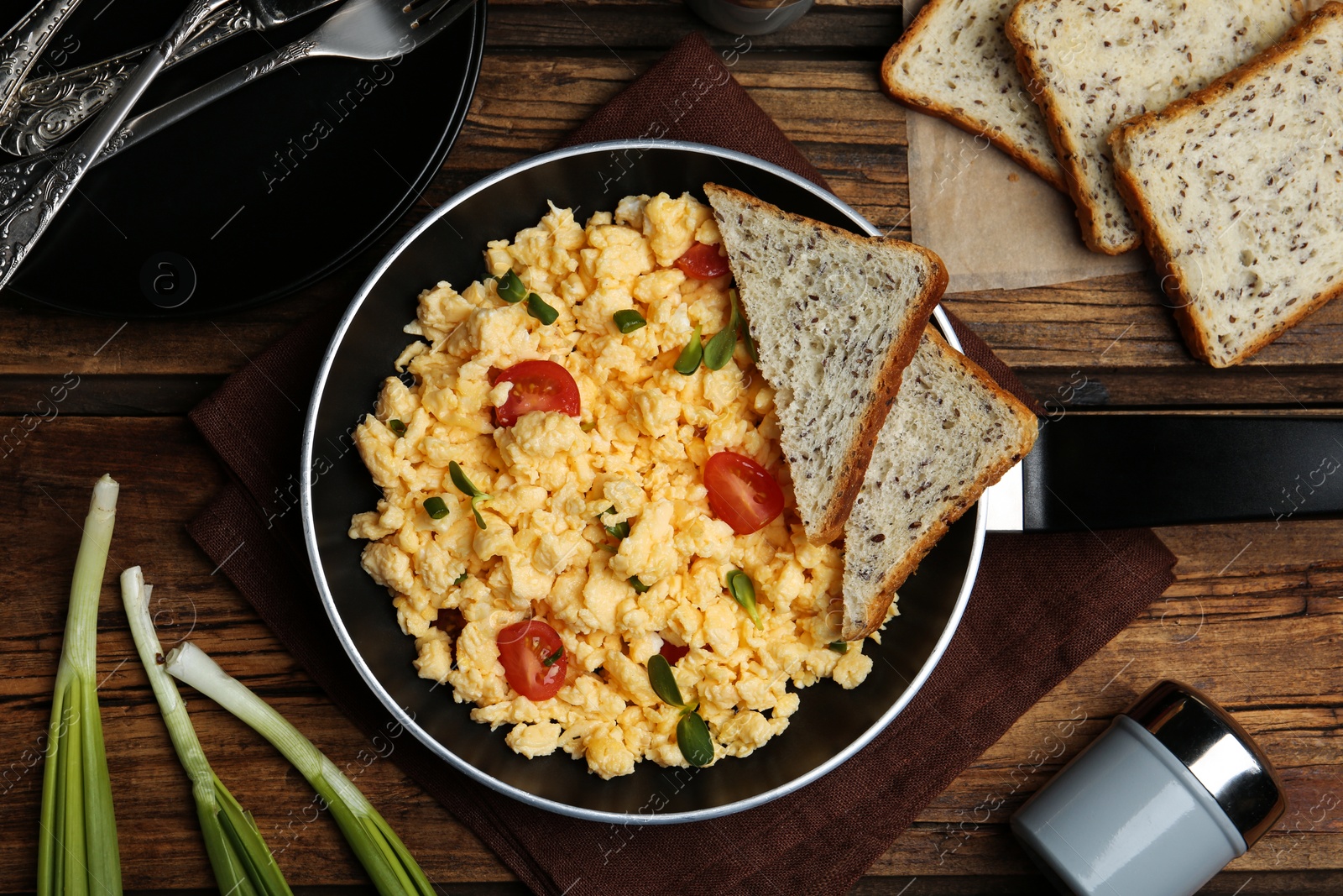 Photo of Tasty scrambled eggs served on wooden table, flat lay