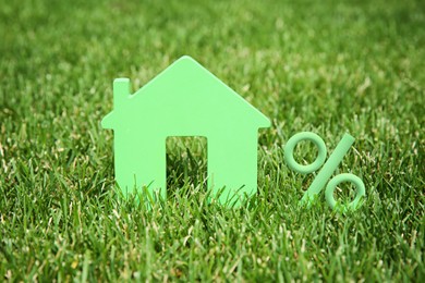 Image of Mortgage concept. House model and percent sign on green lawn