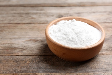 Photo of Bowl with baking soda on wooden table