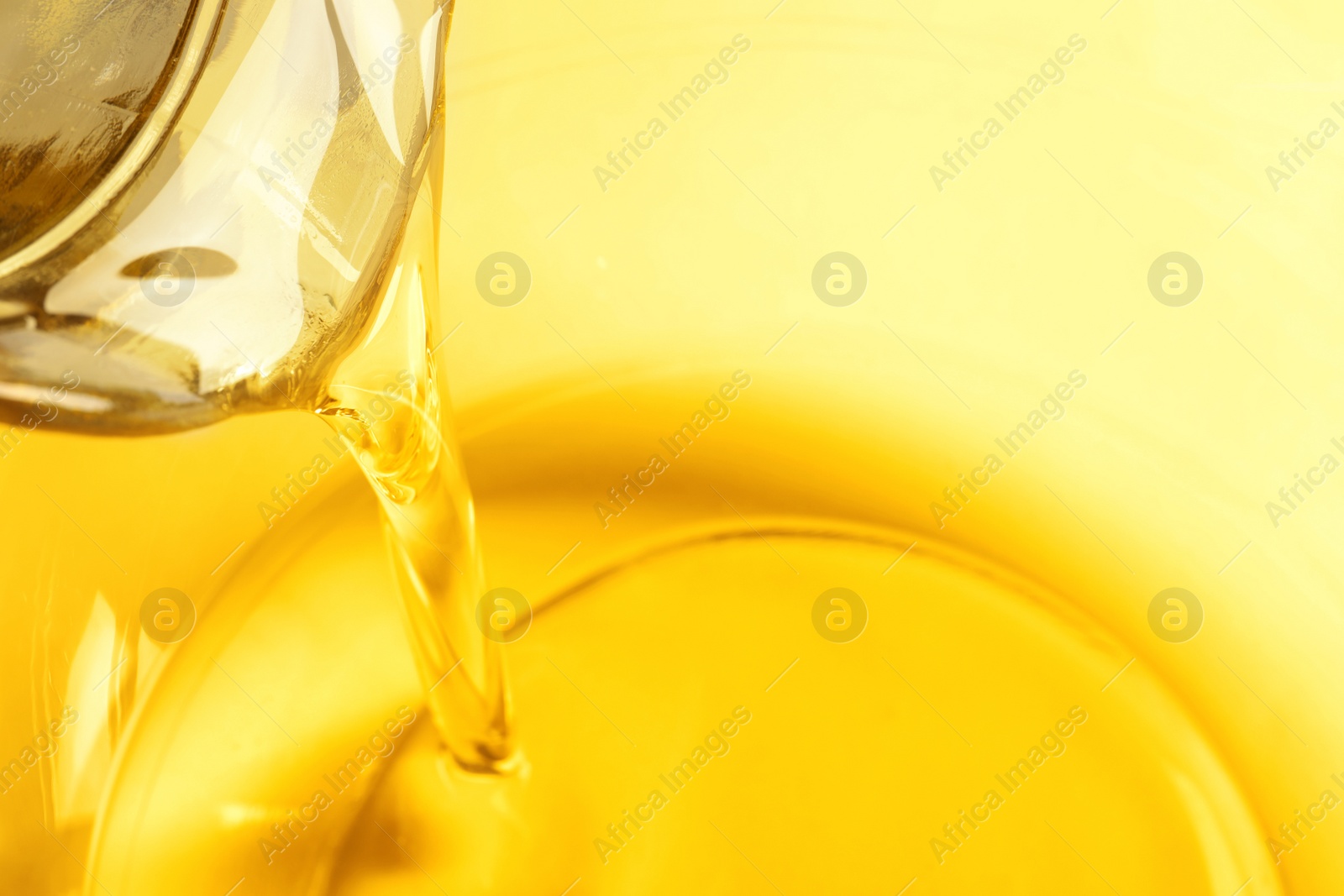 Photo of Pouring cooking oil from jug into bowl, closeup