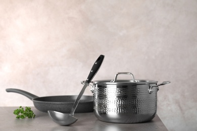 Photo of Set of clean cookware on table against color background. Space for text
