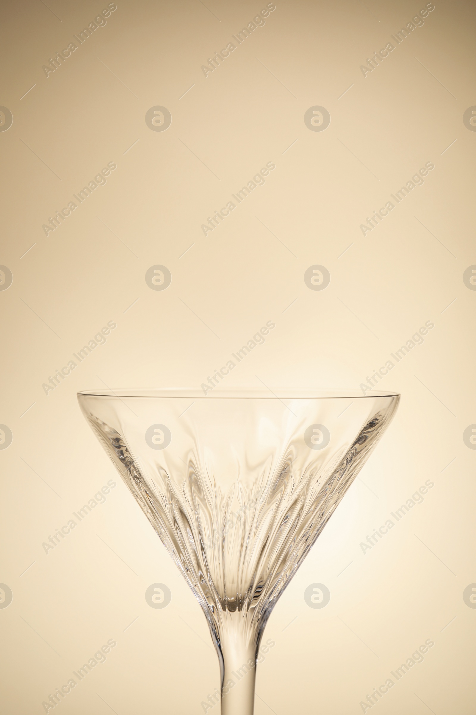 Photo of Elegant empty martini glass on beige background, closeup. Space for text