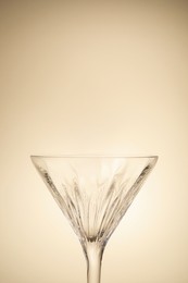 Elegant empty martini glass on beige background, closeup. Space for text