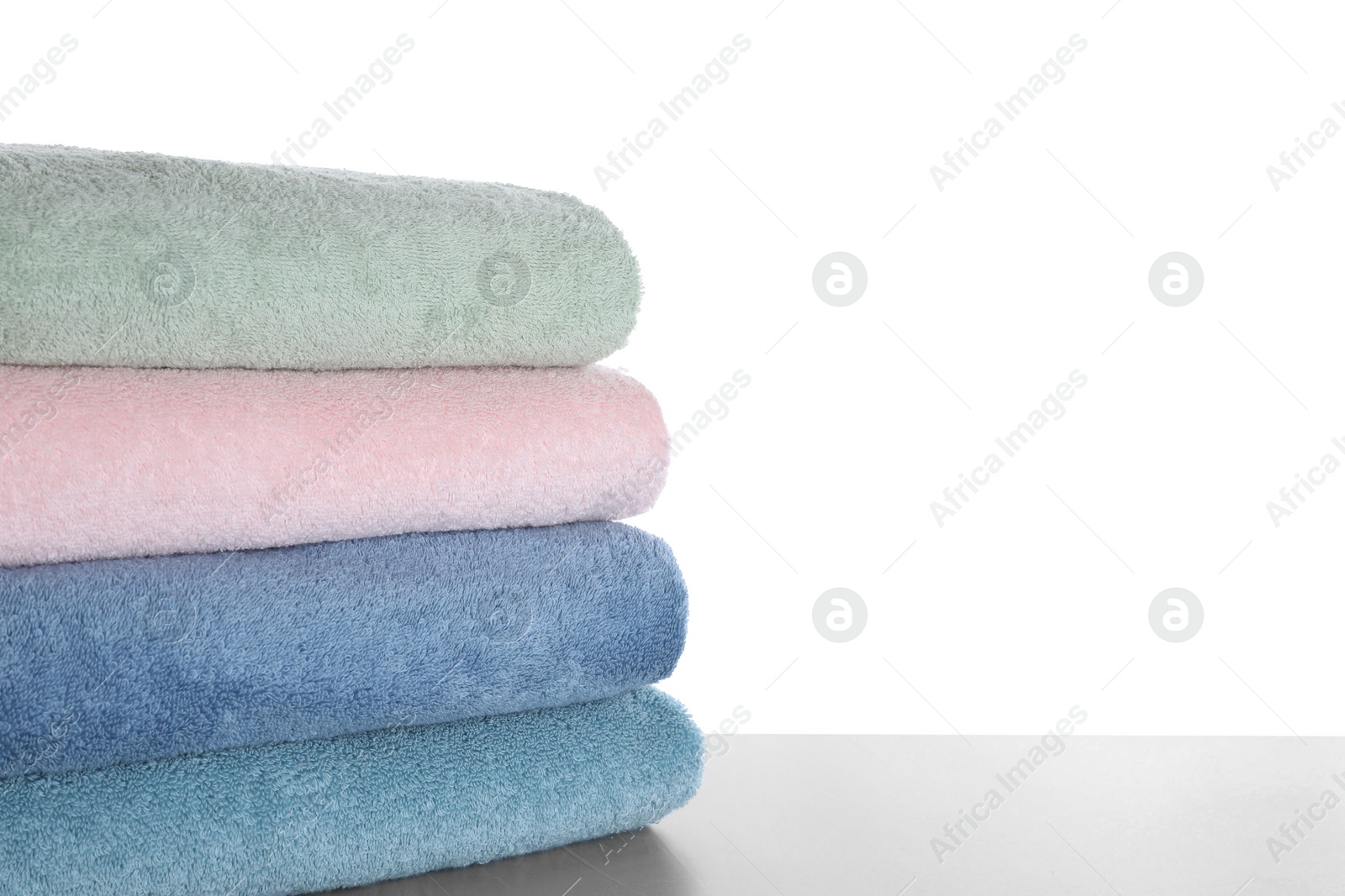 Photo of Fresh towels on light grey table against white background. Space for text