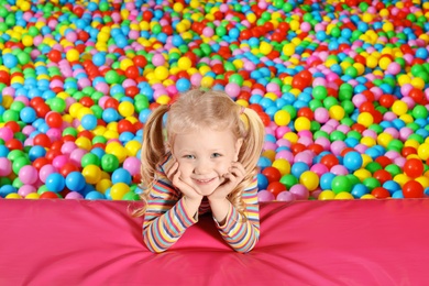 Photo of Cute child playing in ball pit indoors