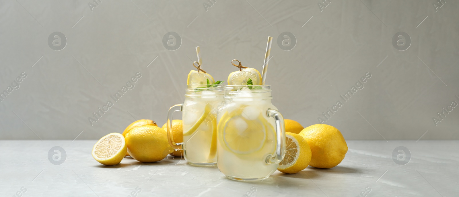Image of Natural lemonade with mint and fresh fruits on light grey marble table. Banner design