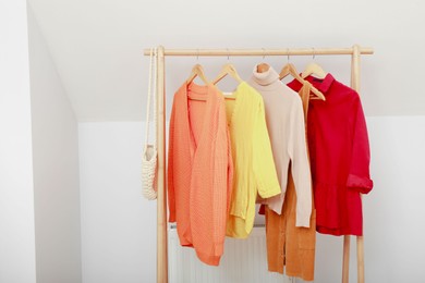 Photo of Stylish clothes hanging on rack in living room