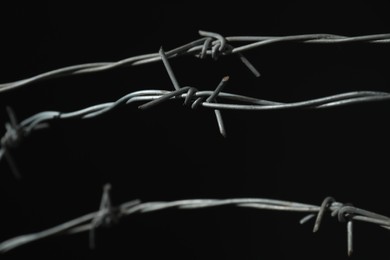 Photo of Shiny metal barbed wire on black background, closeup