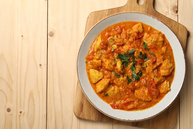 Photo of Delicious chicken curry on wooden table, top view. Space for text