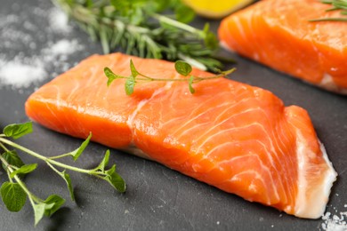 Fresh salmon and ingredients for marinade on black table, closeup