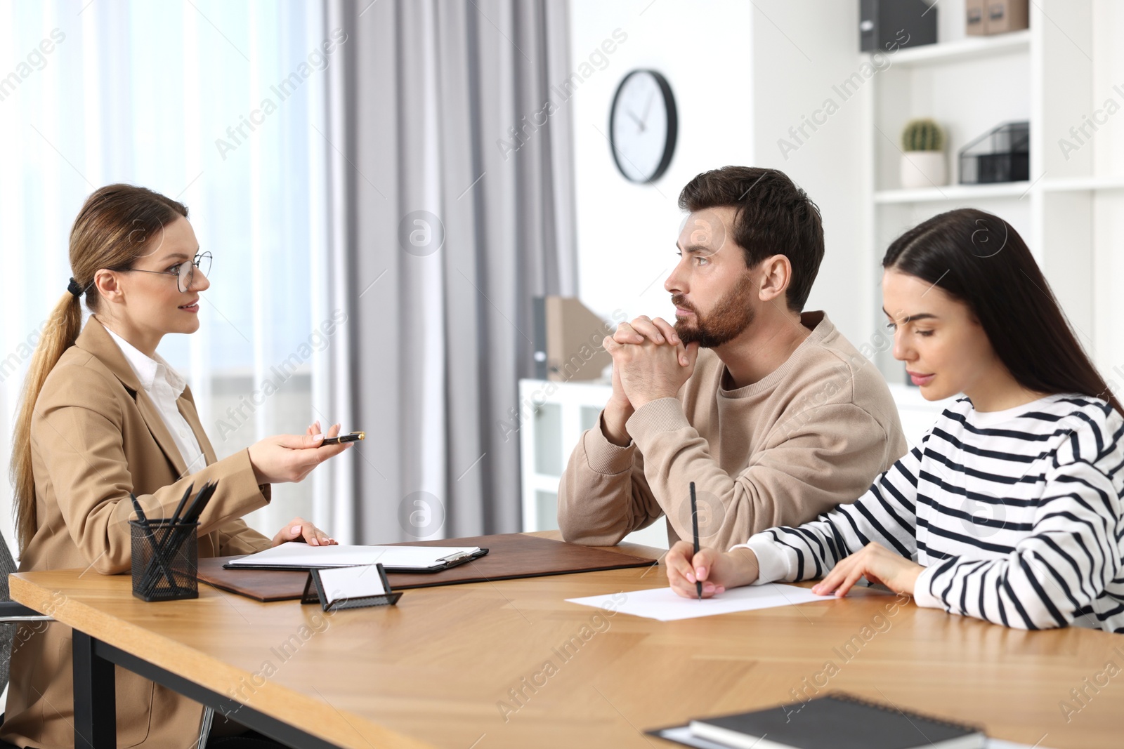 Photo of Couple signing document while having meeting with lawyer in office