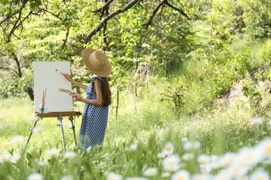 Photo of Little girl painting on easel in picturesque countryside