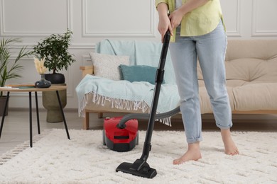 Photo of Woman cleaning carpet with vacuum cleaner at home, closeup. Space for text