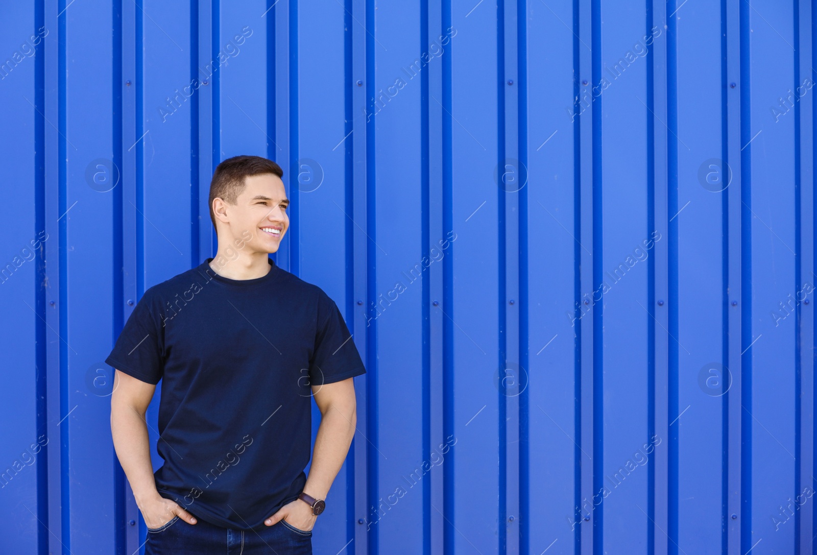 Photo of Young man in black t-shirt near color wall. Mockup for design