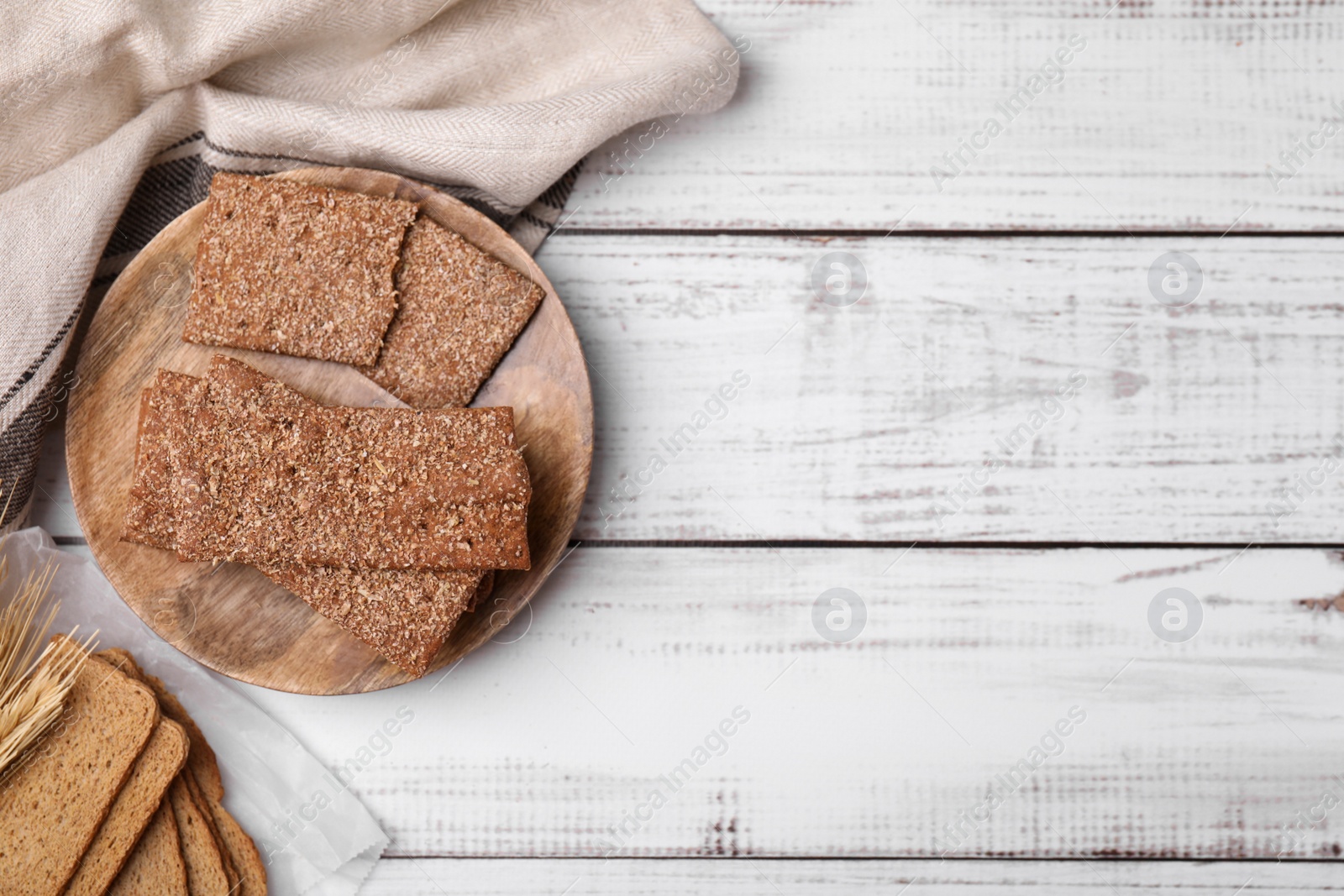 Photo of Rye crispbreads and rusks on white wooden table, flat lay. Space for text