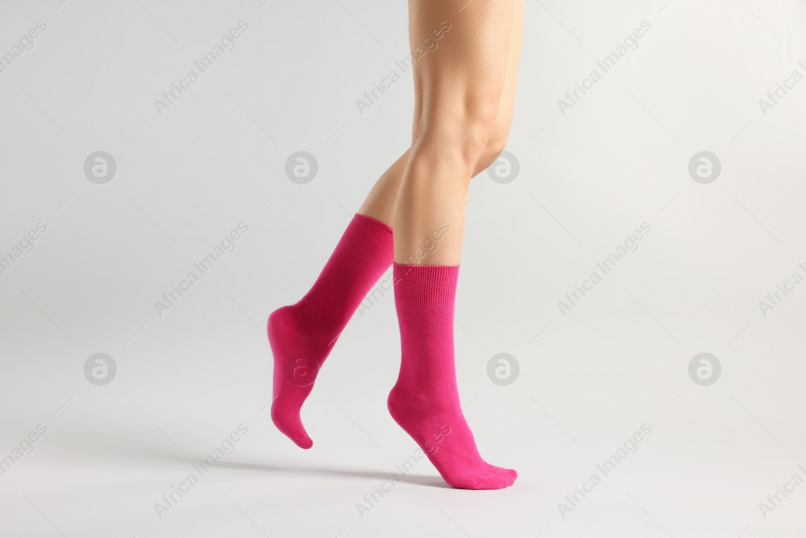 Photo of Woman in stylish bright pink socks on light grey background, closeup