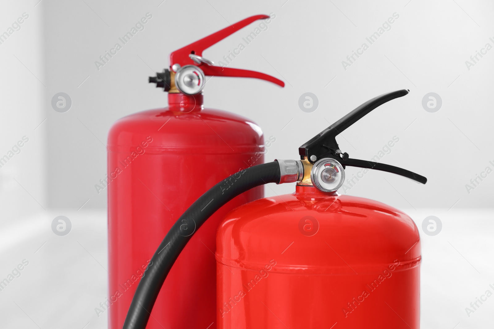 Photo of Two red fire extinguishers indoors, closeup view