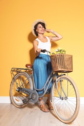 Photo of Portrait of beautiful young woman with bicycle near color wall