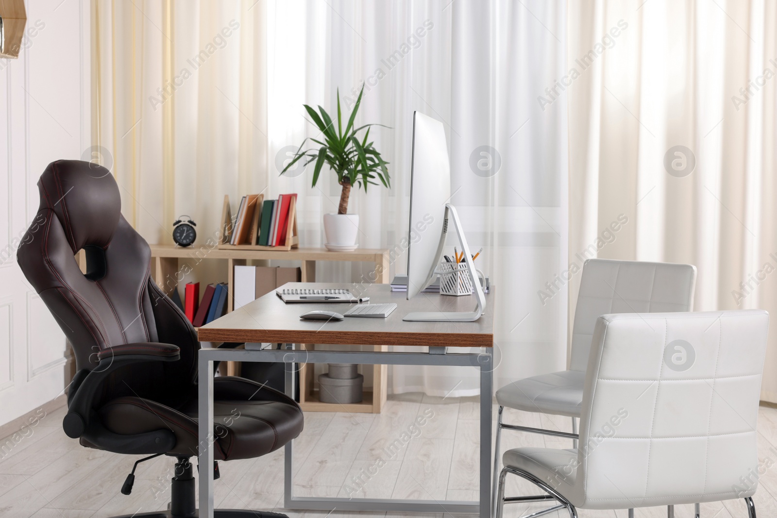 Photo of Director's workplace with wooden table, computer and comfortable armchairs. Interior design