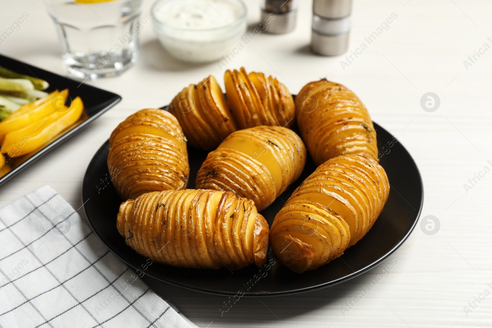 Photo of Delicious homemade Hasselback potatoes served on white wooden table