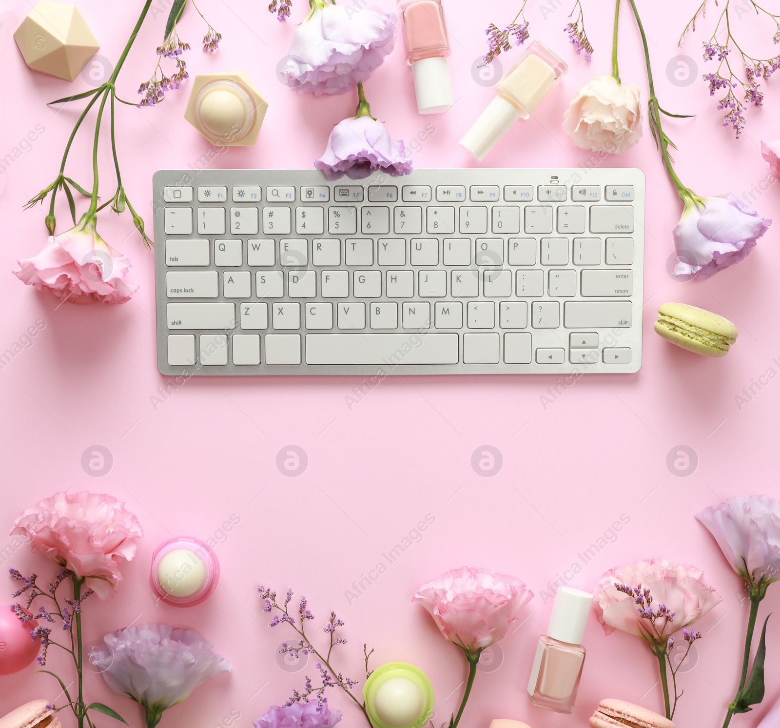 Photo of Flat lay composition with keyboard and flowers on pink background. Beauty blogger's workplace