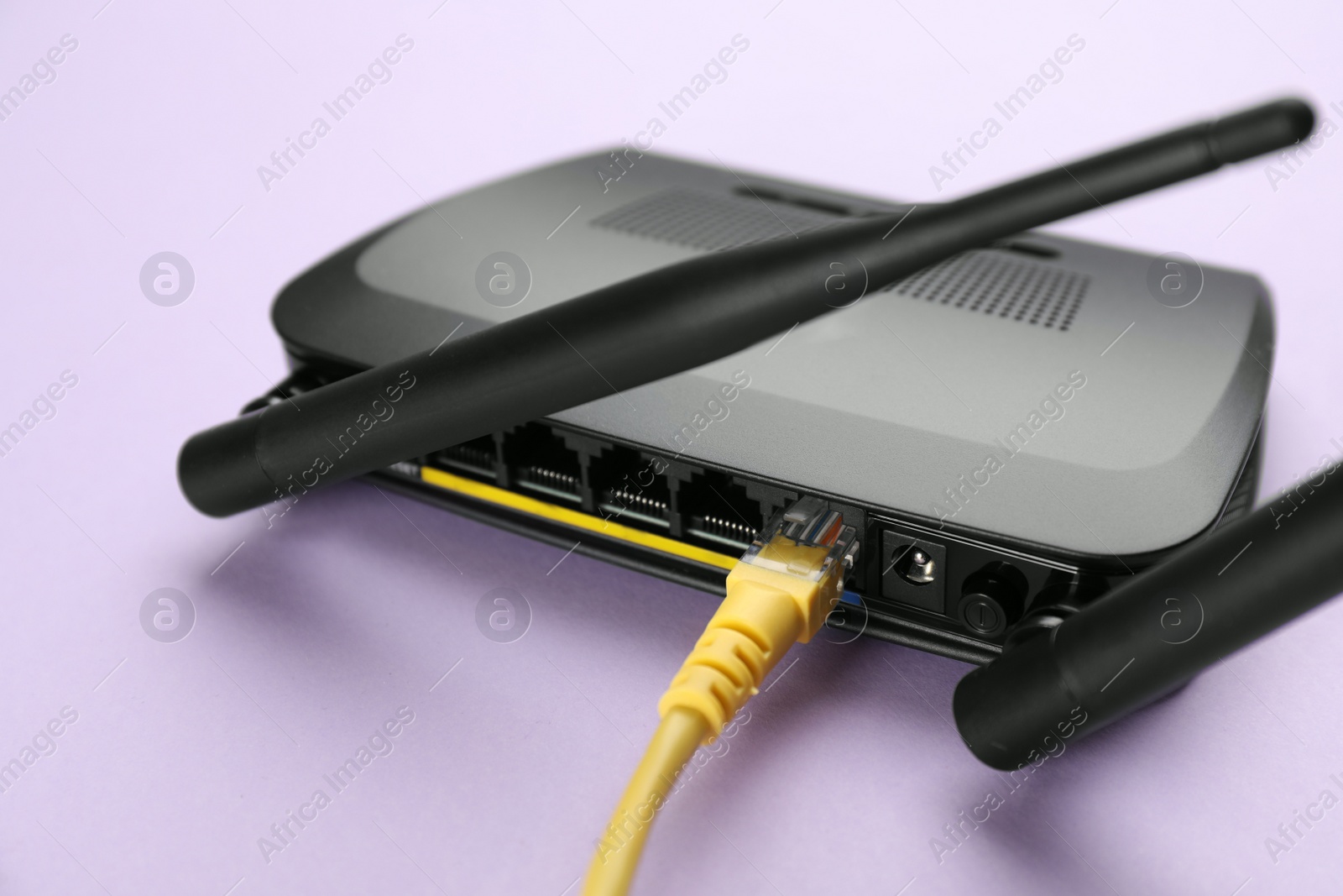 Photo of Modern Wi-Fi router on lilac background, closeup