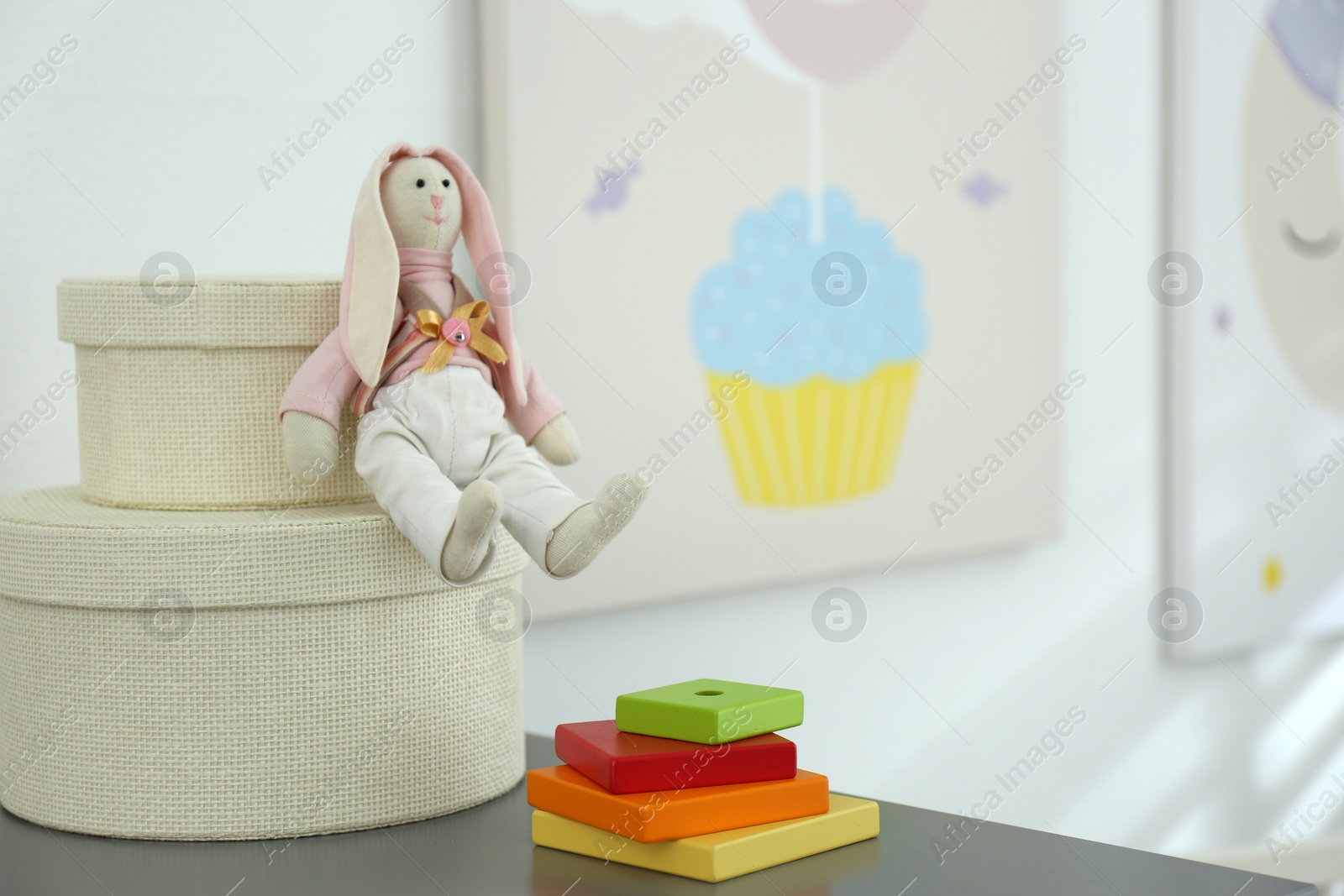 Photo of Boxes and toys on table near wall with cute posters. Interior elements