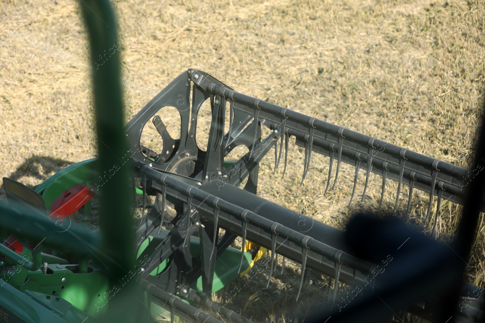 Photo of Modern combine harvester in agricultural field, closeup view of reel