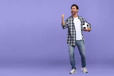 Emotional sports fan with soccer ball on purple background. Space for text