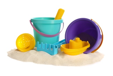 Plastic beach toys on pile of sand against white background