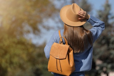 Young woman with stylish backpack on autumn day, back view. Space for text