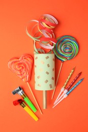Photo of Party cracker and different festive items on orange background, flat lay