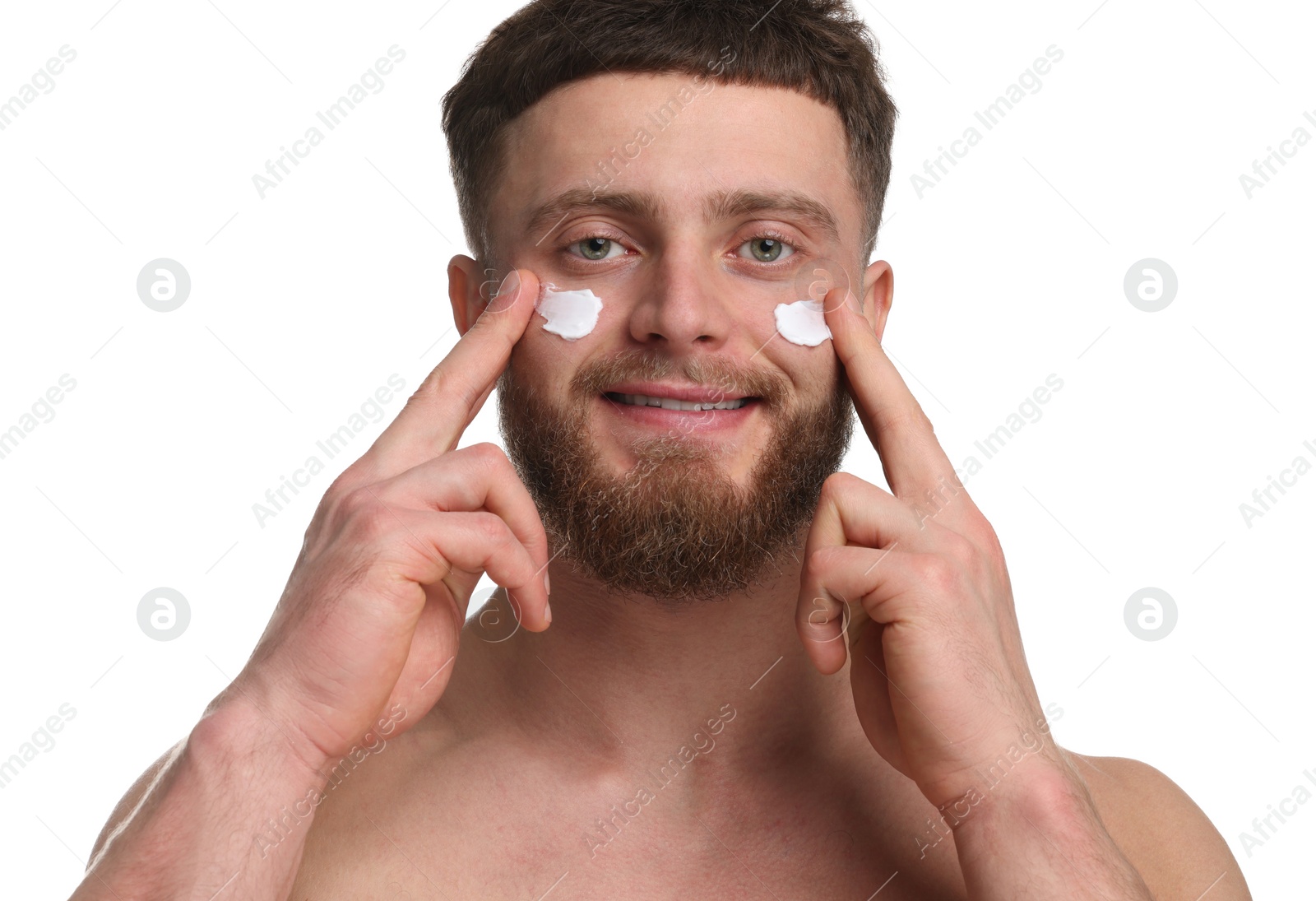 Photo of Handsome man applying moisturizing cream onto his face on white background