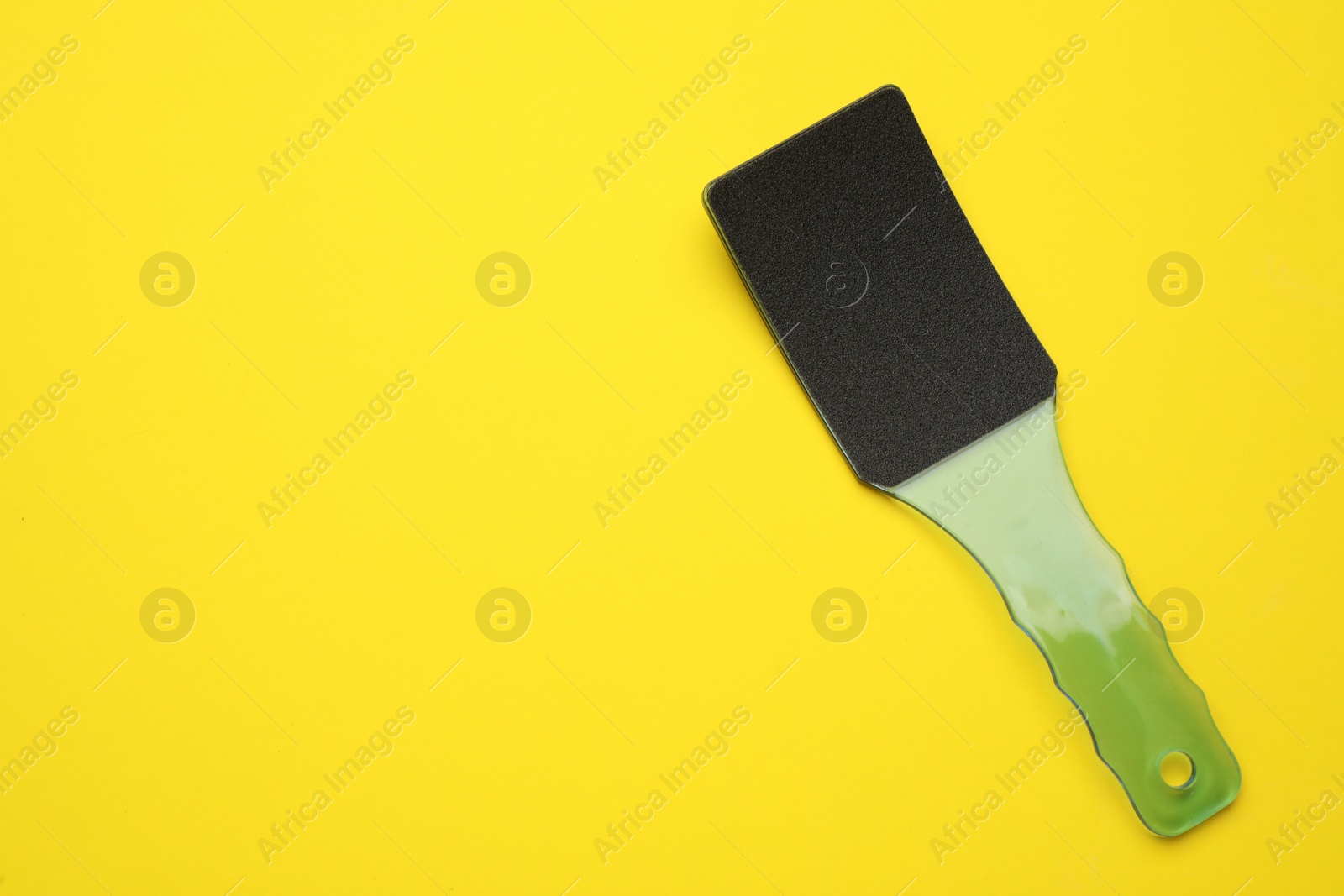 Photo of Foot file on yellow background, top view with space for text. Pedicure tool