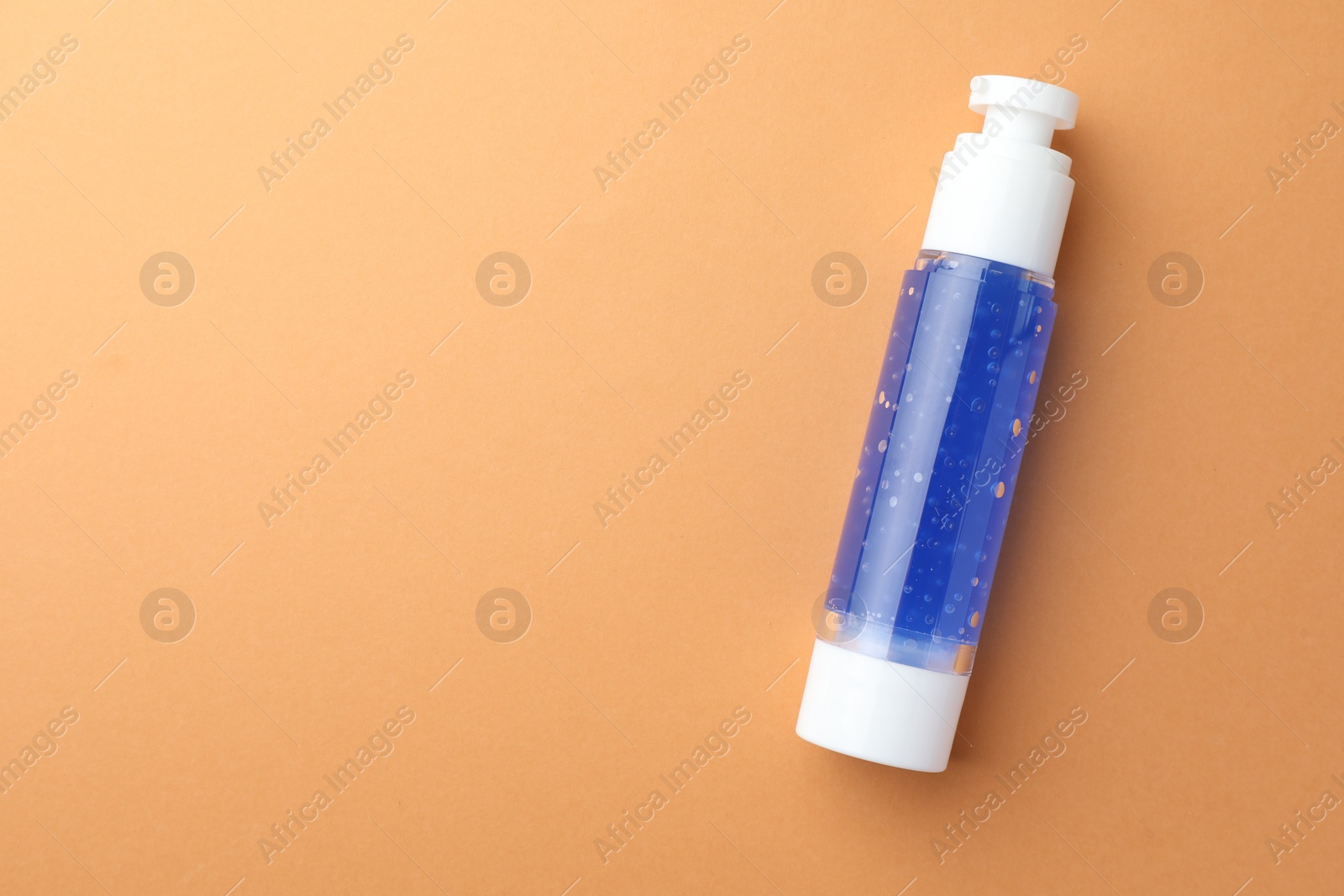 Photo of Bottle of cosmetic product on orange background, top view. Space for text