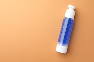 Bottle of cosmetic product on orange background, top view. Space for text