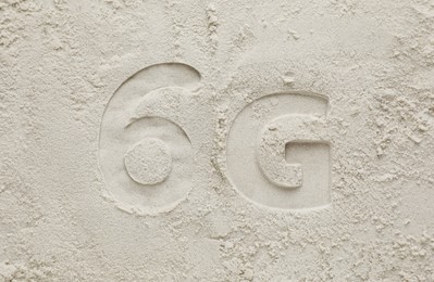 Photo of 6G technology, Internet concept. Print of number and letter on white sand, flat lay